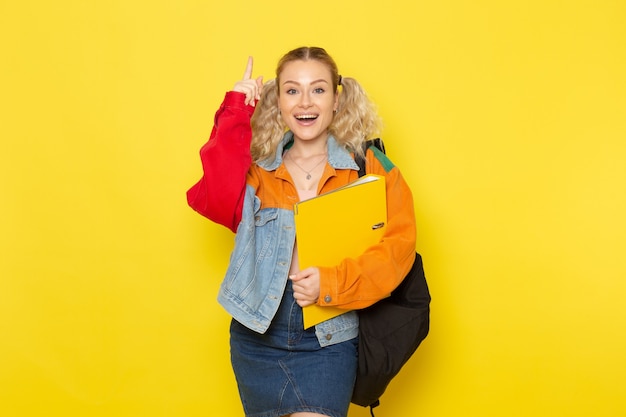 female student young in modern clothes holding yellow files smiling on yellow