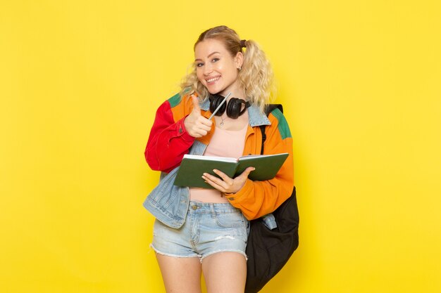 female student young in modern clothes smiling holding copybooks on yellow