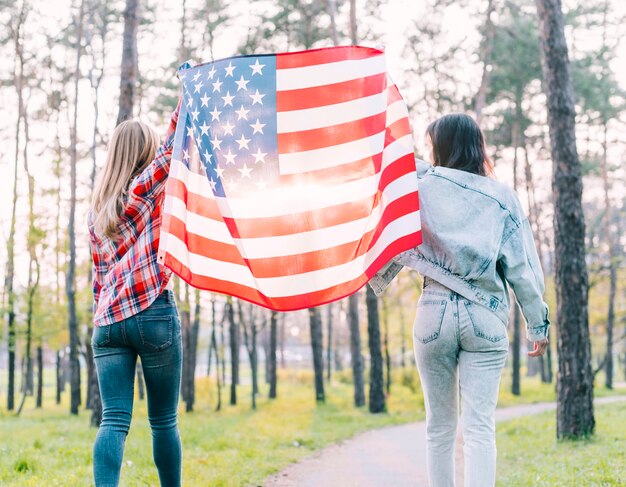 Female students holding flag of USA outdoors