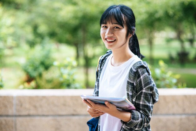 Female students stand on the stairs and hold books.