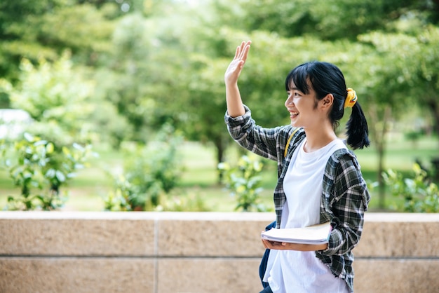 Female students stand on the stairs and hold books.