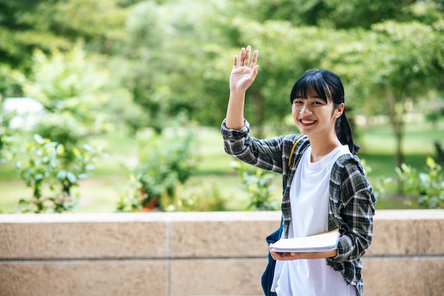 Female students stand on the stairs and hold books.