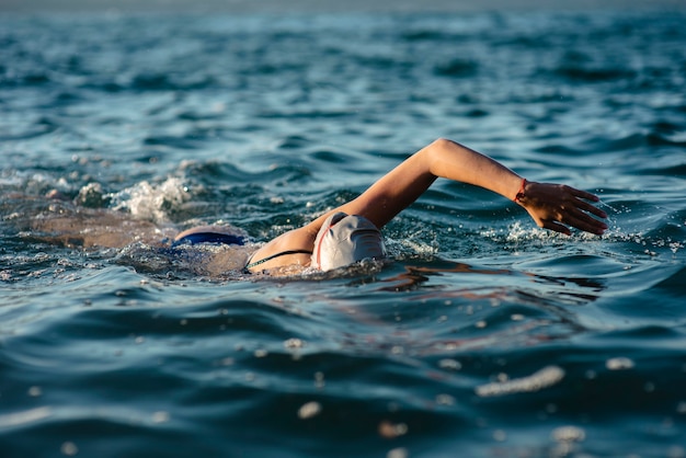 Female swimmer with cap and goggles swimming in water