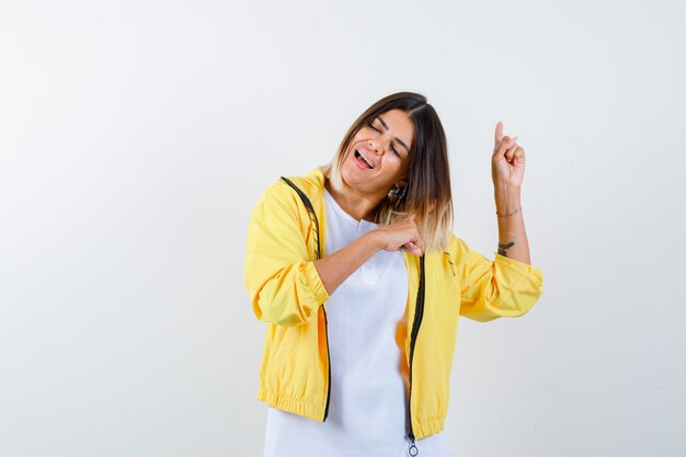 Female in t-shirt, jacket pointing up and looking energetic , front view.