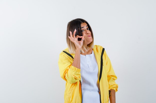 Female in t-shirt, jacket showing ok gesture and looking confident , front view.