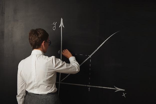 Free Photo female teacher in conservative outfit teaching a math class at the blackboard