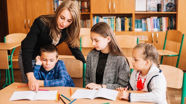 Female teacher helping pupils in studying process