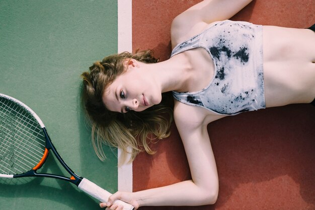 Free photo female tennis player lying on ground