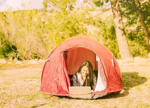 Free photo female traveler working with laptop in camping