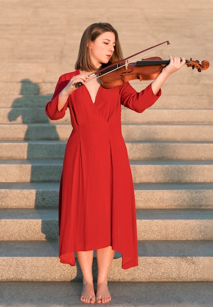 Free photo female violinist playing the instrument on steps