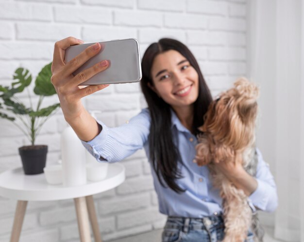 Female vlogger at home with smartphone and dog