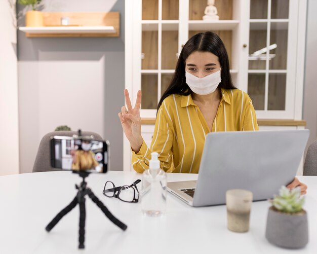 Female vlogger at home with smartphone and laptop