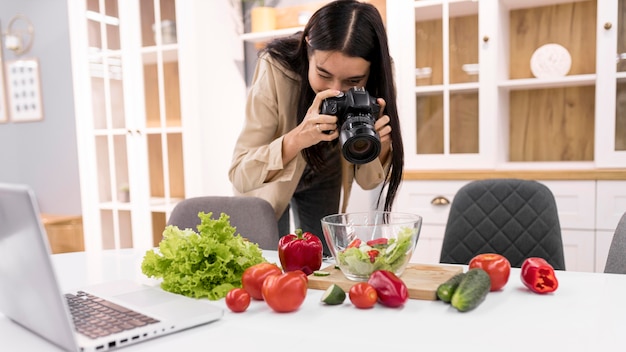 Free photo female vlogger taking pictures with camera