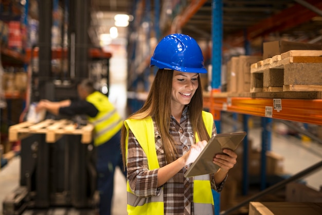 Free photo female warehouse worker holding tablet checking inventory in distribution warehouse