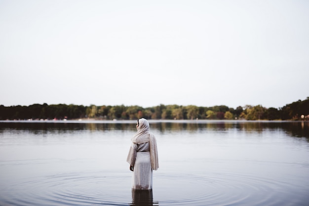 Female wearing a biblical robe while standing in the water - concept cleaning her sins