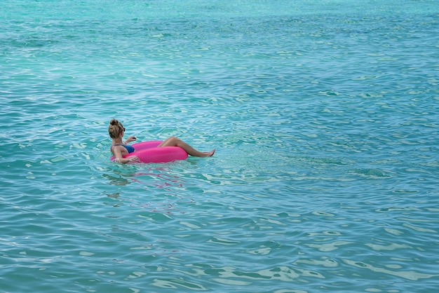 Female wearing a bikini in a pink float in the sea