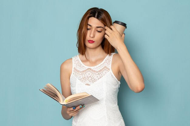 female in white blouse and blue jeans holding coffee cup and book