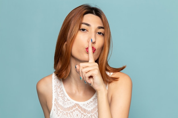 Free photo female in white dress posing showing silence sign