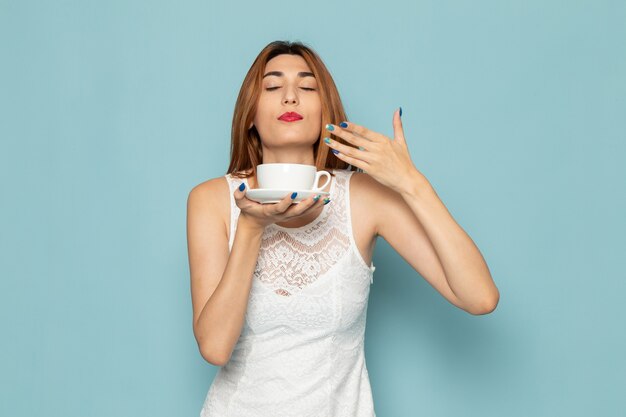 female in white dress smelling tea