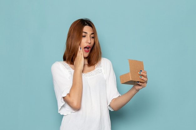 female in white dress surprised after opening little box