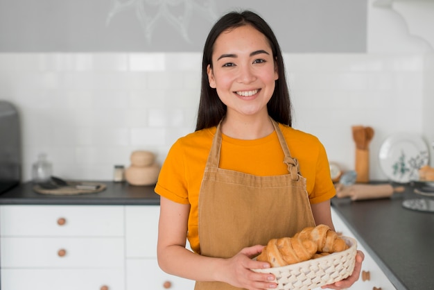 Female with apron holding basket of croissant