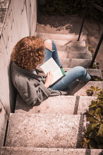 Free photo female with book sitting on stone stair