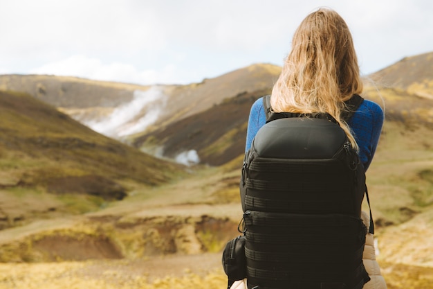 Free photo female with hiking backpack looking at the beautiful mountains in iceland