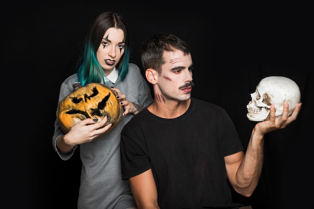 Free photo female with pumpkin and man with skull