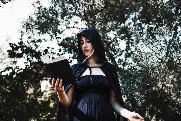 Female wizard with spellbook in woods daytime