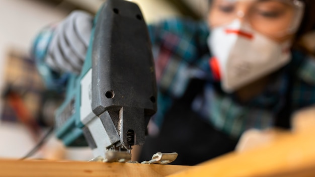 Female working in workshop with hammer drill close up