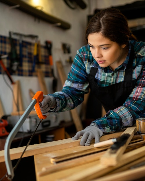 Free photo female in workshop cutting wood plank