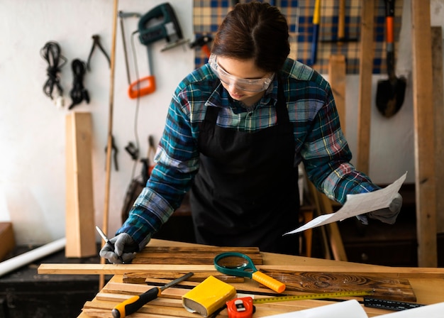 Free photo female in workshop measure wood plank