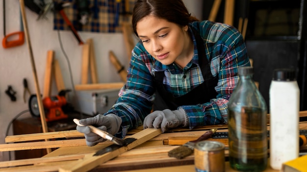 Female in workshop painting wood plank