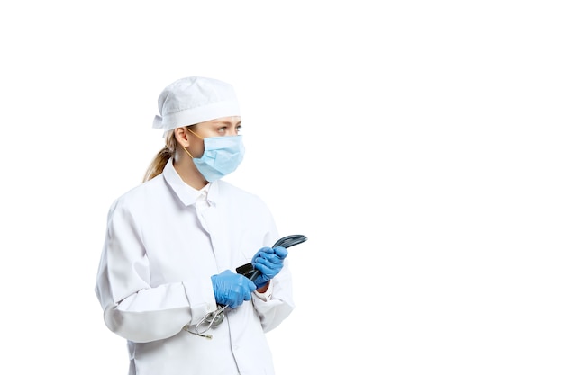 Female young doctor with stethoscope and face mask isolated on white  wall