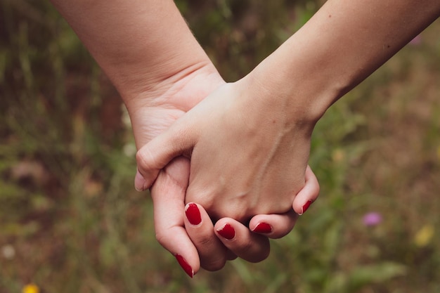 Females romantically holding hands in the woods