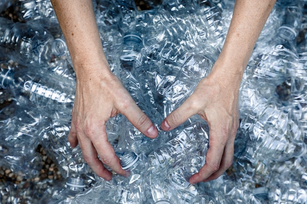 Free photo femals hands grabbing plastic bottles to collect and trash them