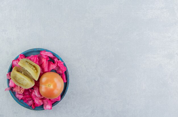 Fermented red cabbage, whole and slice tomatoes in a wooden plate on the marble surface