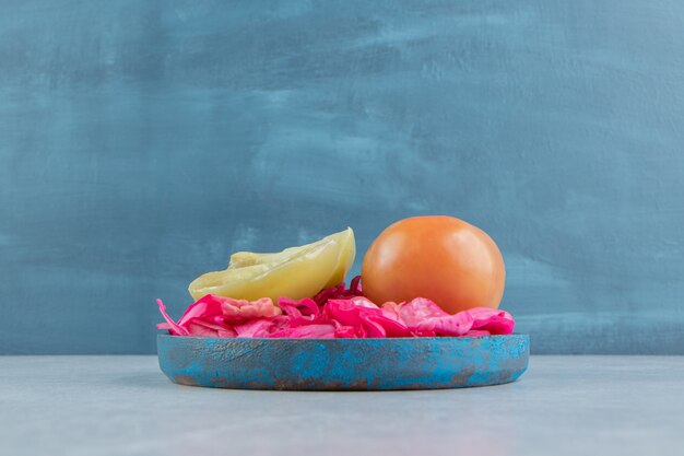 Fermented red cabbage, whole and slice tomatoes in a wooden plate    