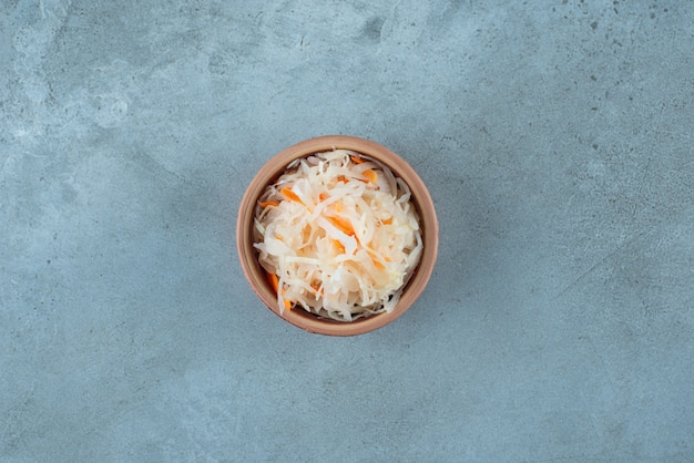 Free Photo fermented sauerkraut with carrots in a clay bowl, on the blue table. 