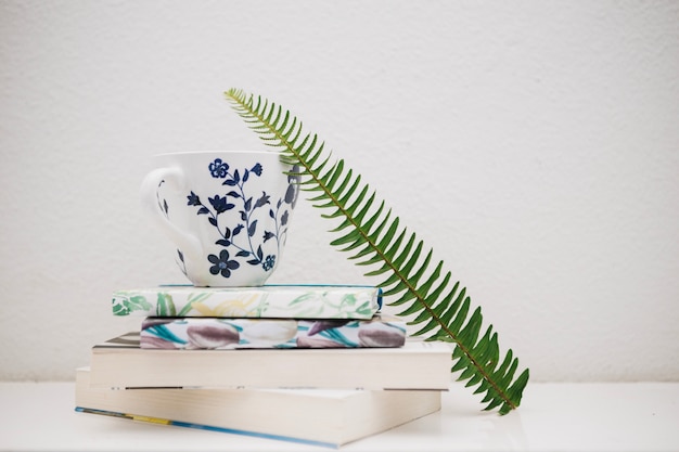 Fern leaf near cup and books