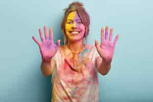 Free photo fesitaval of holy, fun concept. pretty cheerful european young woman covered with colored paints