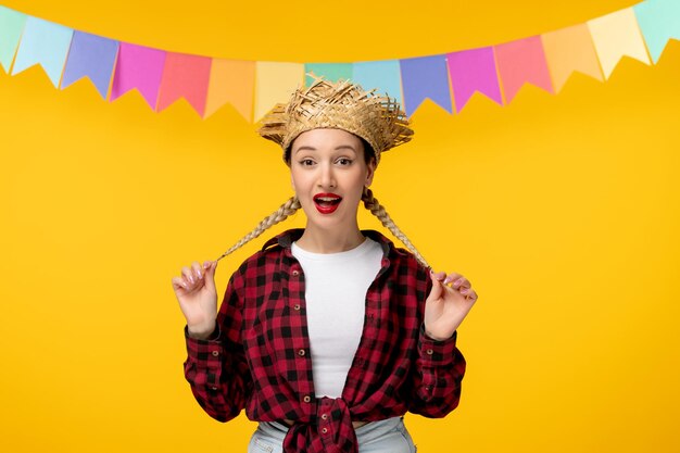 Festa junina blonde cute girl in straw hat brazilian festival with colorful flags holding braids