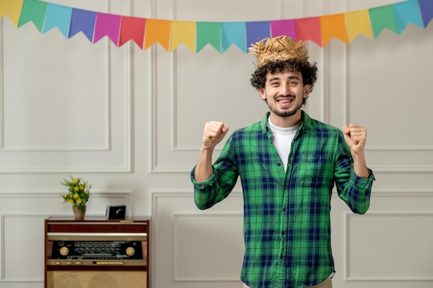 Free Photo festa junina cute young guy in straw hat with retro radio and colorful flags excited with fists up