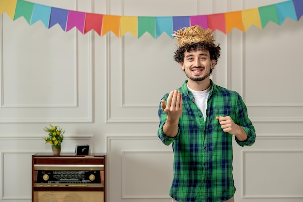 Free Photo festa junina cute young guy in straw hat with retro radio and colorful flags inviting with hands