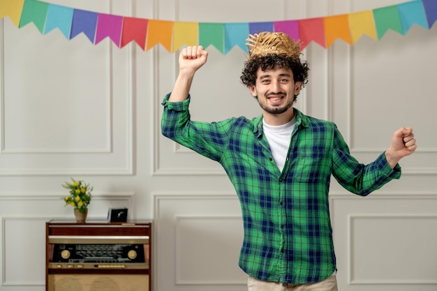 Free Photo festa junina cute young guy in straw hat with retro radio and flags dancing happily