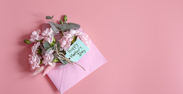 Festive composition with an envelope with fresh flowers and the inscription Happy Mother's Day flat lay.