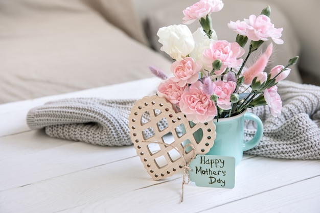 A festive composition with fresh flowers in a vase, decorative elements and a wish for a happy mother's day on a postcard.