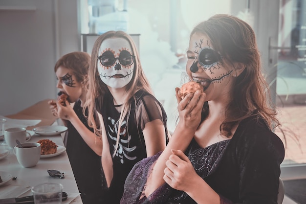 Free photo festive halloween party in process - kids are sitting next to the table and have tasty treats.