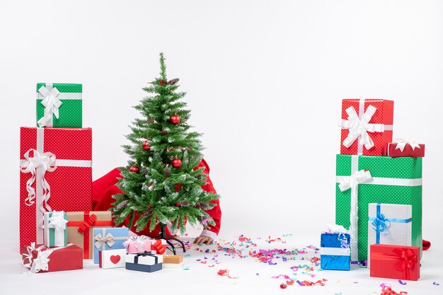 Festive holiday mood with santa claus hiding behind decorated xsmas tree on white background