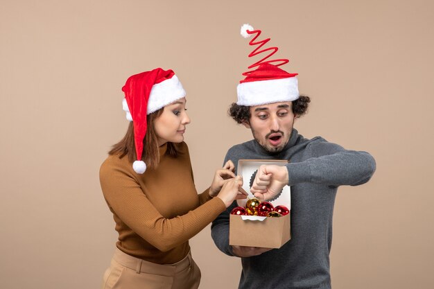 Festive mood with excited cool couple wearing red santa claus hats on gray footage